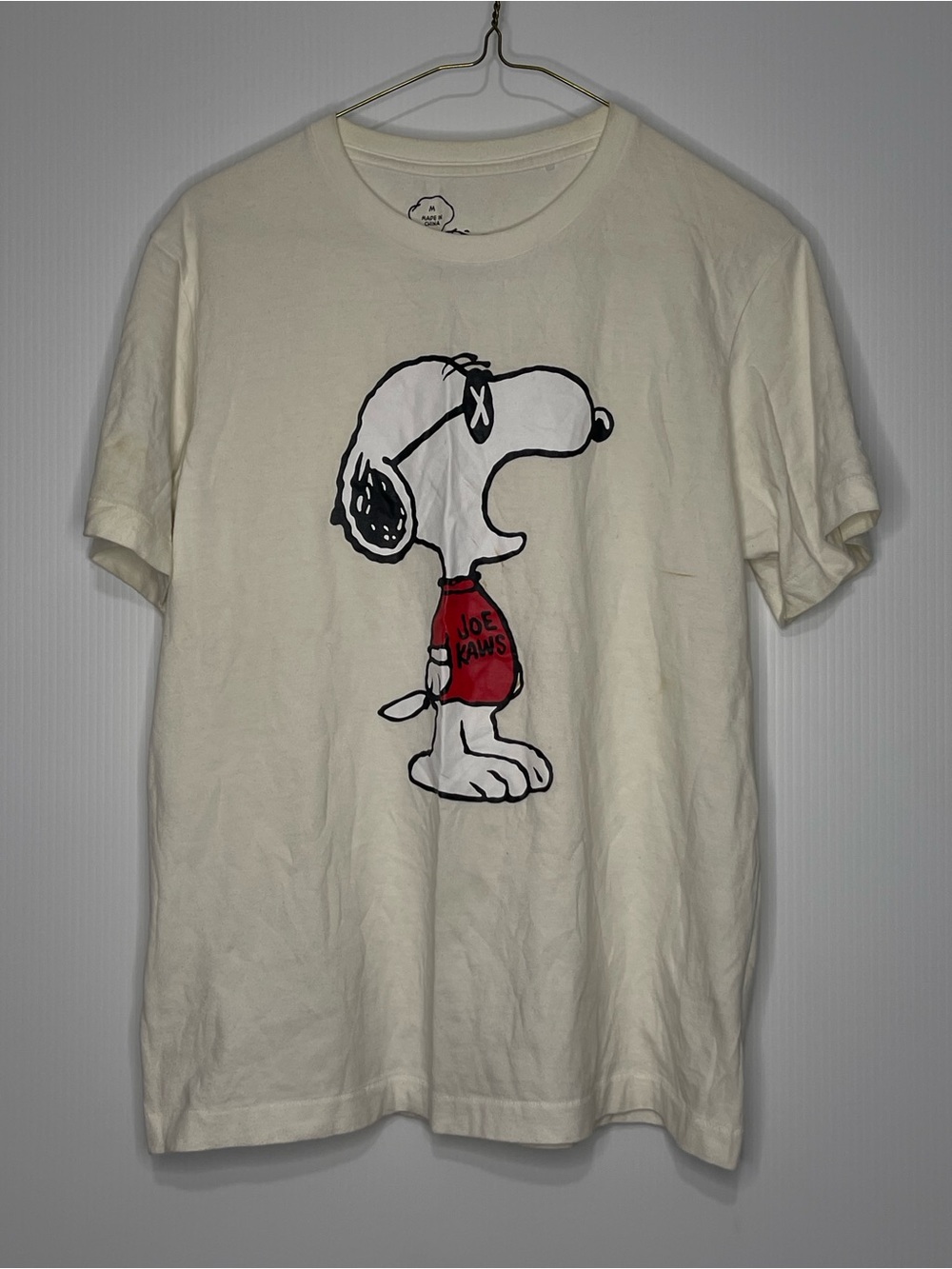 Kaws X Peanuts Cream Tee Featuring Snoopy Graphic with Red Shirt